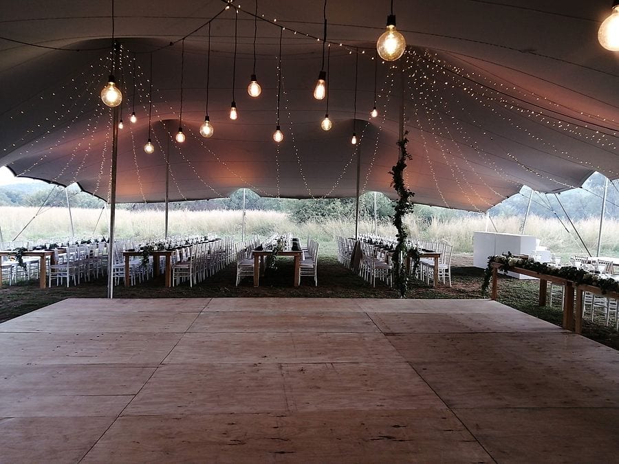 Hanging filament bulbs over a dance floor under a stretch tent