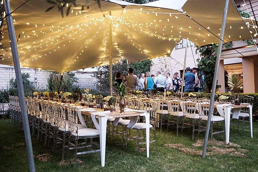 Long wedding tables under a stretch tent strung with fairy lights