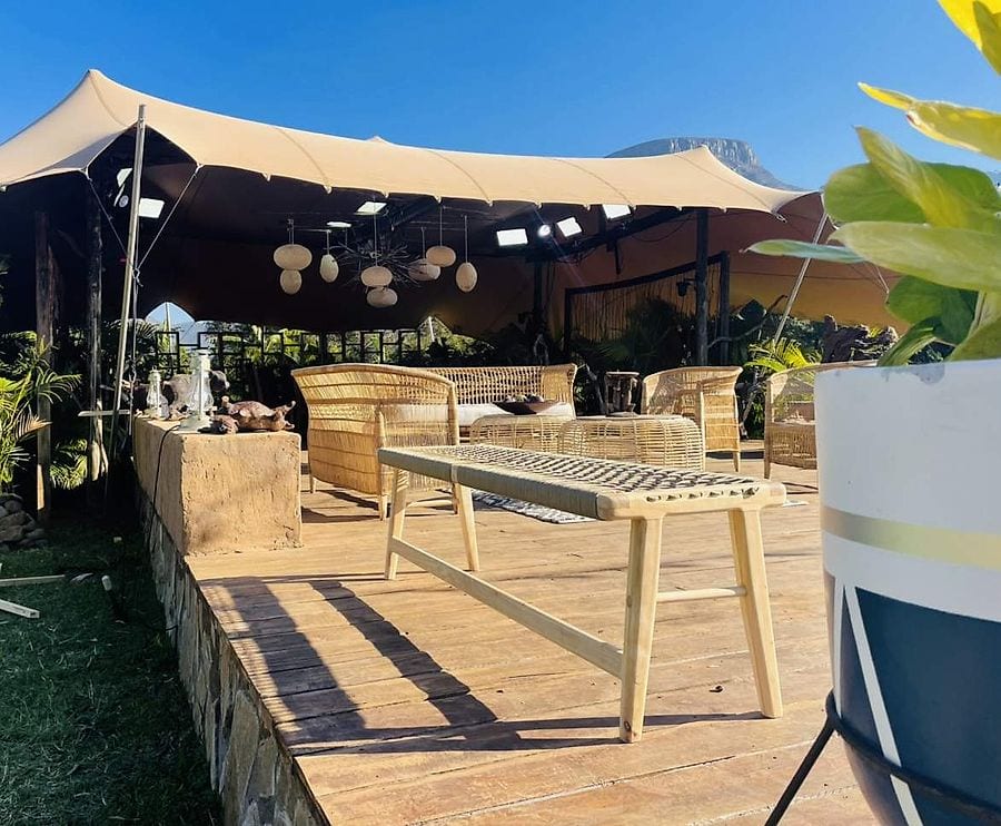 A beige stretch tent over a deck with lanterns and wooden tables