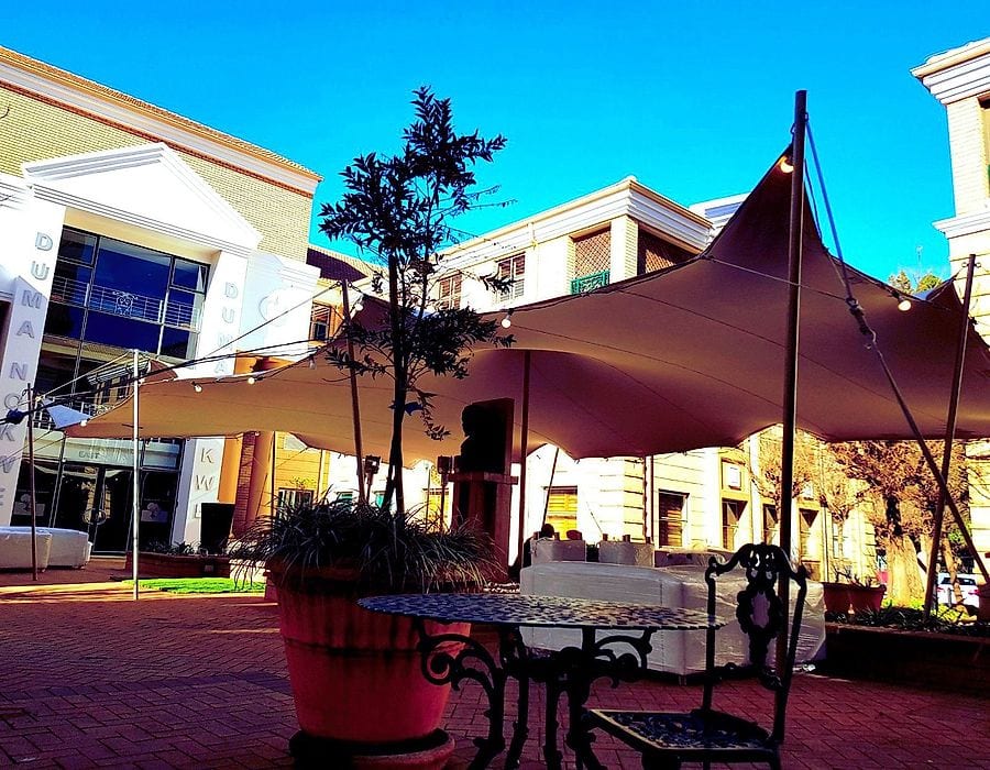 A maroon stretch tent in a sunny courtyard