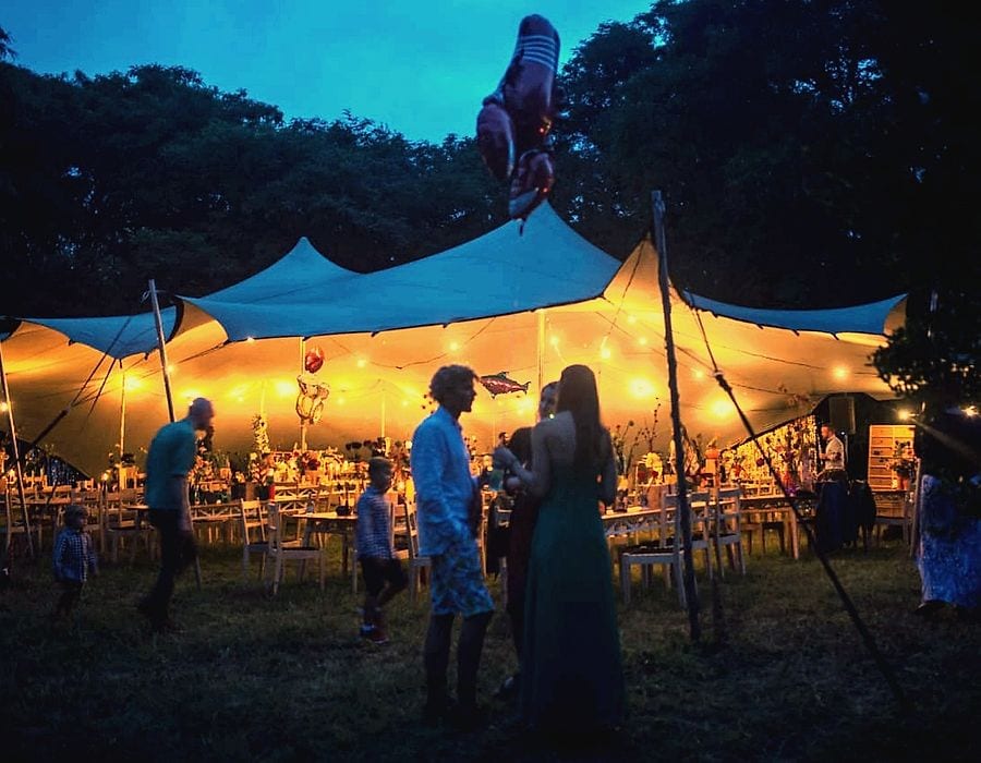 Guests at a night garden party under a glowing stretch tent