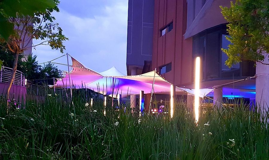 Stretch tents lit purple in a hotel garden at dusk