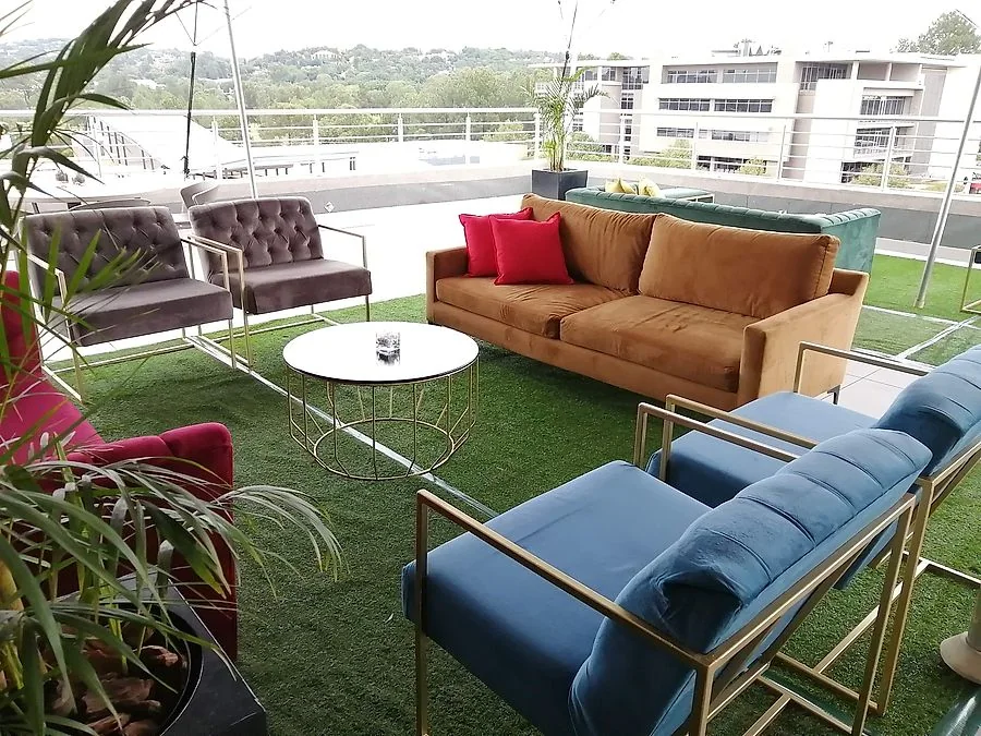 Lounge sofas and a coffee table set out on astro turf under a stretch tent