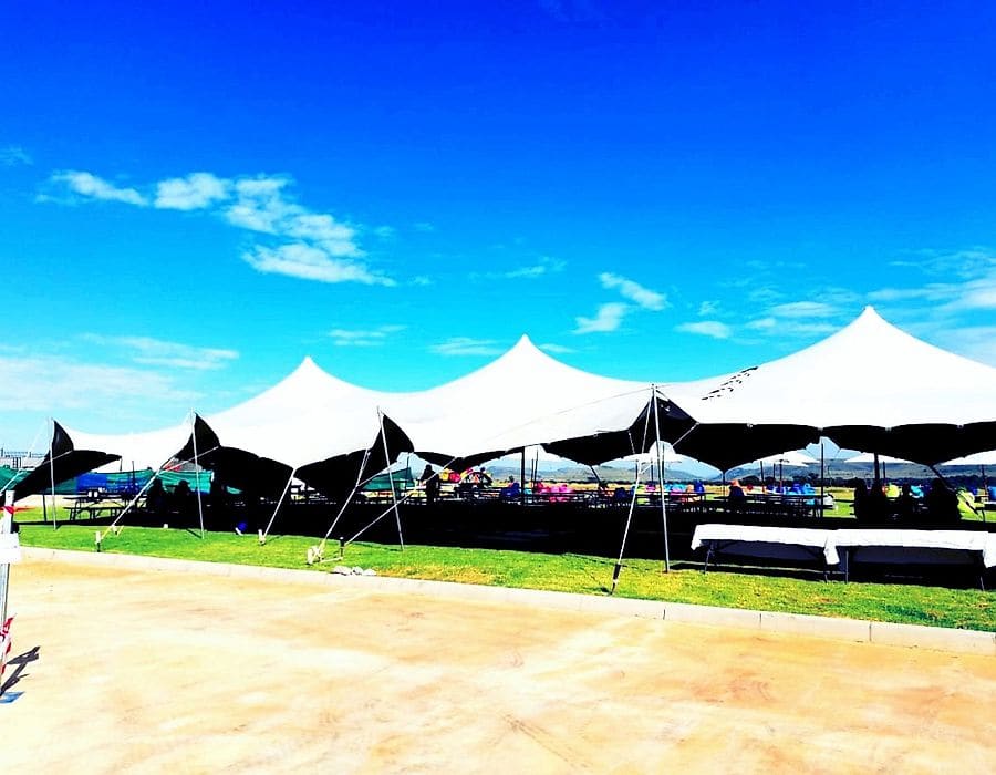 A row of joined white stretch tents under a blue sky