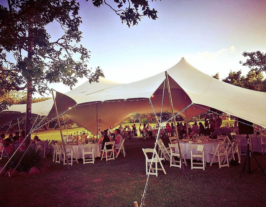 A stretch tent over garden tables at sunset