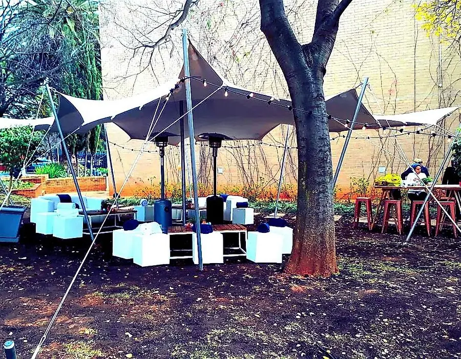 A stretch tent rigged around a tree with white cube seating
