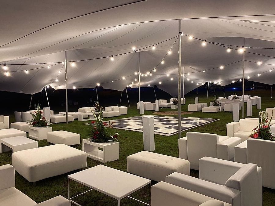 A black and white dance floor beside white lounge furniture at night